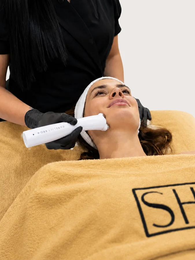 Practitioner using PureLift Pro Plus on a client lying under a towel